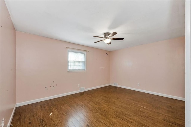 unfurnished room with visible vents, ceiling fan, wood finished floors, and baseboards