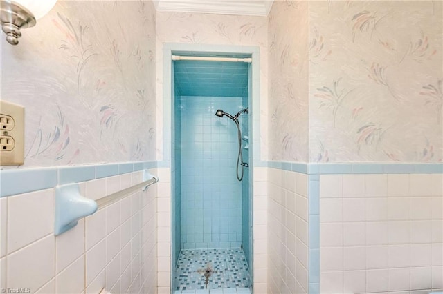 full bath featuring ornamental molding, a tile shower, tile walls, and wallpapered walls