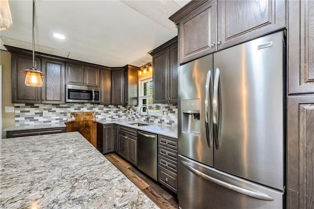 kitchen with a sink, stainless steel appliances, dark wood-style floors, dark brown cabinetry, and backsplash