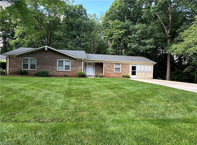 ranch-style house with a front lawn, brick siding, concrete driveway, and view of scattered trees