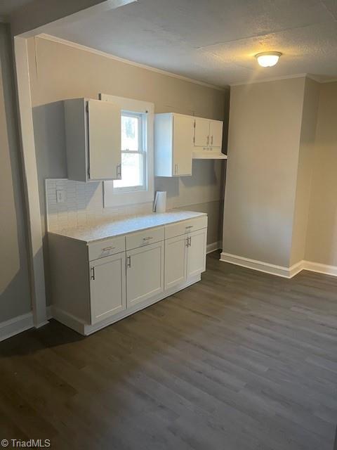 kitchen featuring dark hardwood / wood-style flooring, a textured ceiling, ornamental molding, and white cabinets