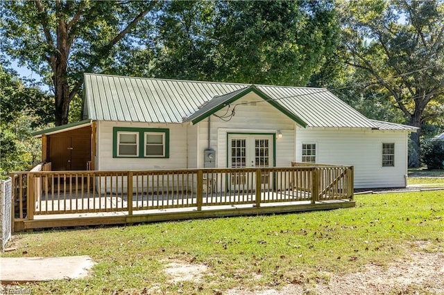 rear view of property with a wooden deck, a lawn, and french doors