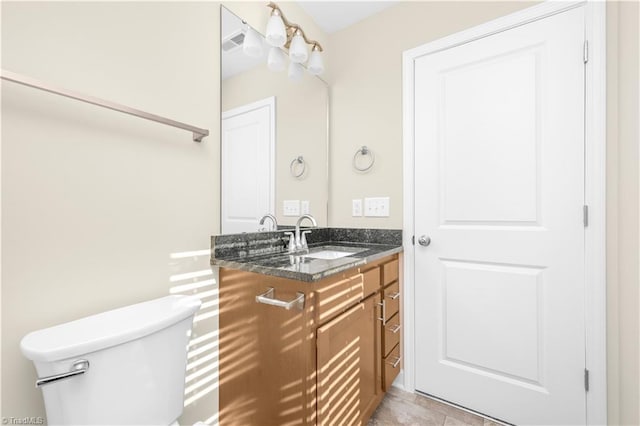 bathroom with toilet, vanity, and tile patterned flooring