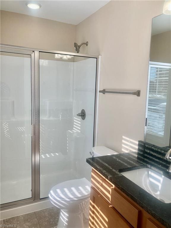 bathroom featuring toilet, tile patterned flooring, walk in shower, and vanity