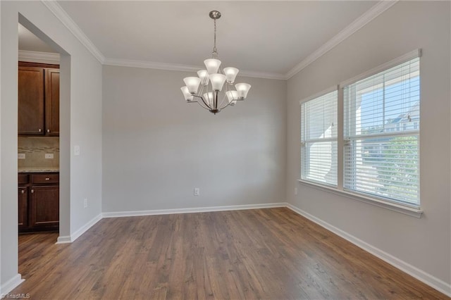 empty room with crown molding, dark hardwood / wood-style flooring, and an inviting chandelier