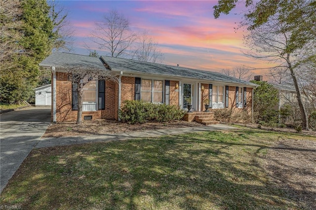 ranch-style house with brick siding, driveway, and a front lawn