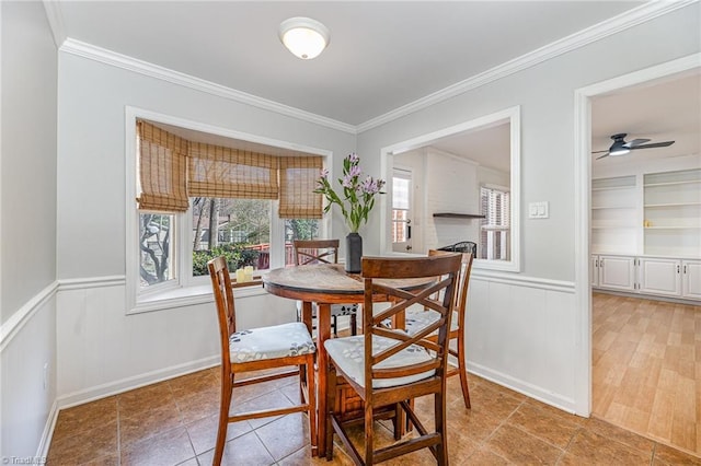 dining room with crown molding, built in shelves, and wainscoting