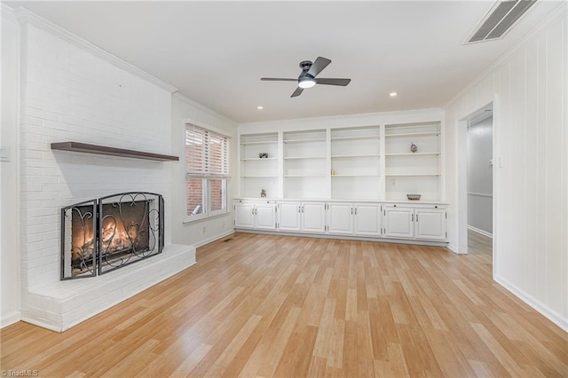 unfurnished living room featuring crown molding, light wood-style flooring, a fireplace, and visible vents