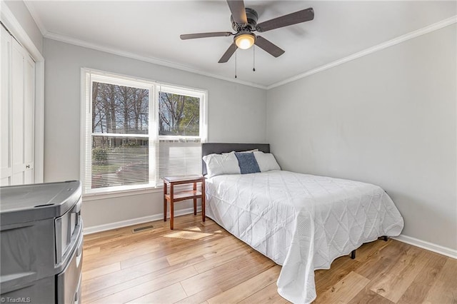 bedroom featuring visible vents, light wood-style floors, baseboards, and ornamental molding