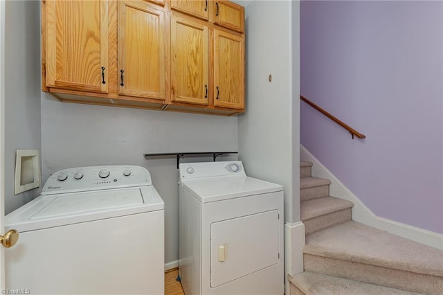 clothes washing area with washer and dryer and cabinets