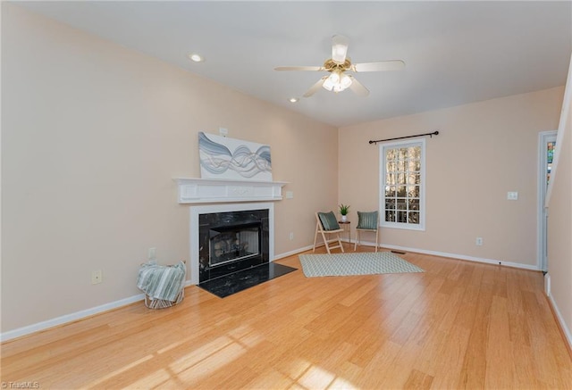 unfurnished living room featuring hardwood / wood-style floors, a premium fireplace, and ceiling fan