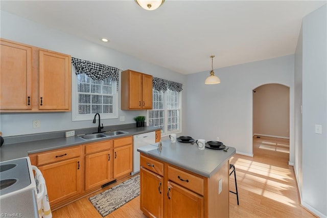 kitchen featuring pendant lighting, sink, white appliances, a breakfast bar, and a center island