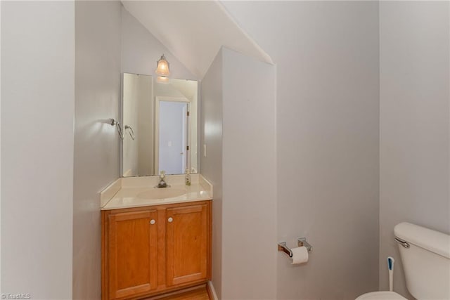 bathroom featuring vanity, toilet, and vaulted ceiling