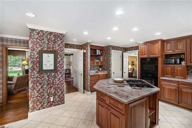 kitchen featuring light stone counters, crown molding, black appliances, light tile patterned floors, and a kitchen island