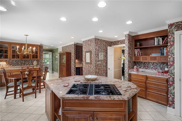 kitchen featuring an inviting chandelier, black gas stovetop, crown molding, hanging light fixtures, and a kitchen island