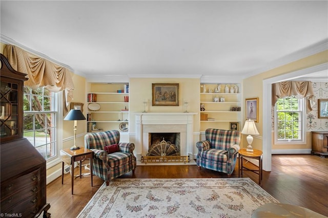 sitting room with built in features, wood-type flooring, and ornamental molding