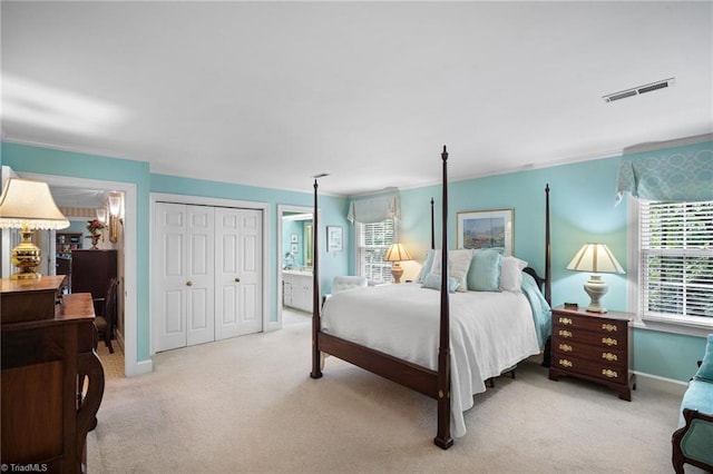 bedroom with ensuite bathroom, crown molding, and light colored carpet