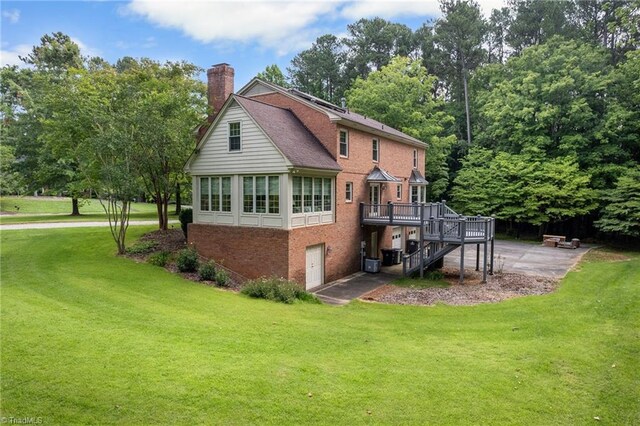 back of house with a sunroom, a patio area, a deck, and a yard