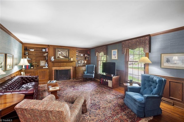 living room featuring hardwood / wood-style floors, crown molding, and built in shelves