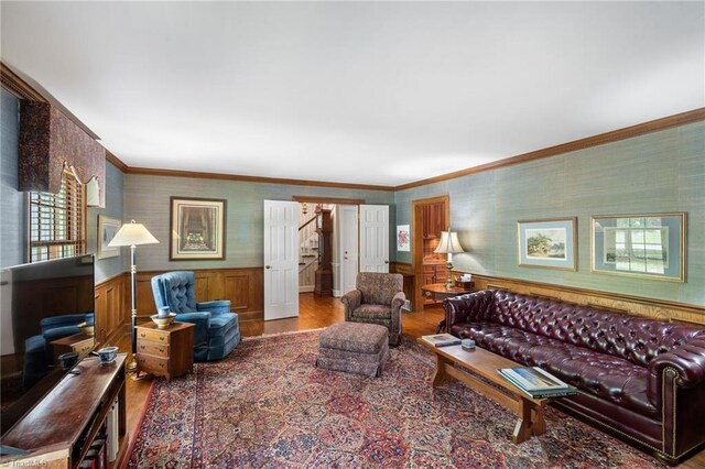 living room featuring wood-type flooring, crown molding, and a healthy amount of sunlight