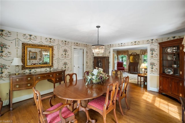 dining space with hardwood / wood-style floors, ornamental molding, and a notable chandelier