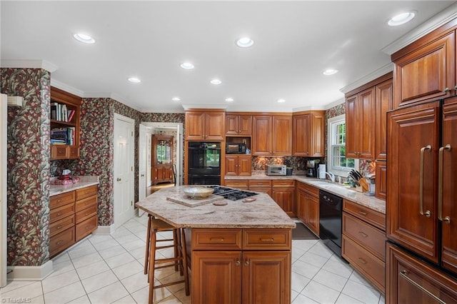 kitchen featuring a center island, a kitchen bar, black appliances, crown molding, and light stone counters