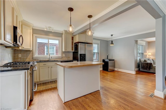 kitchen featuring light wood-style flooring, a sink, stainless steel appliances, crown molding, and tasteful backsplash