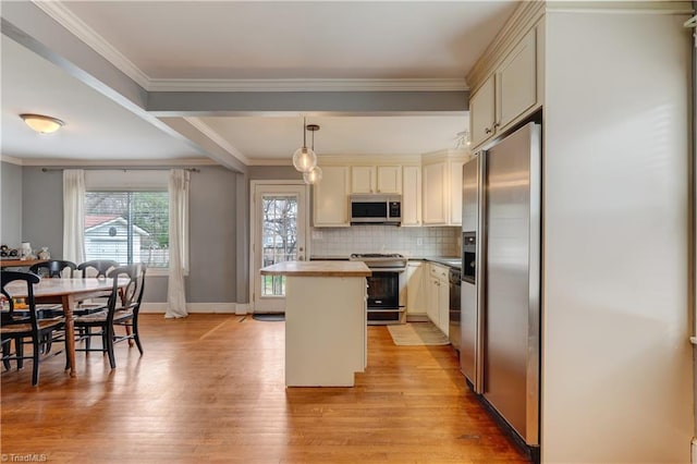 kitchen featuring light wood finished floors, decorative backsplash, appliances with stainless steel finishes, crown molding, and a center island