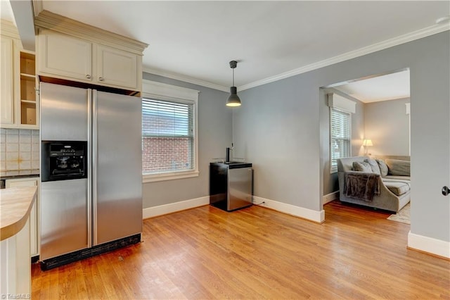 kitchen with light wood-style flooring, ornamental molding, stainless steel fridge with ice dispenser, decorative backsplash, and baseboards