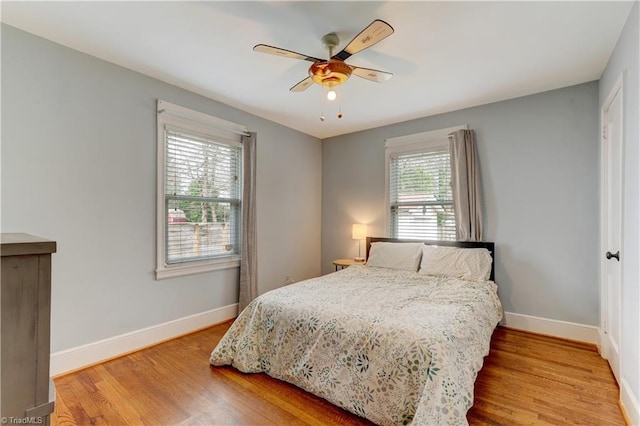 bedroom with a ceiling fan, wood finished floors, and baseboards