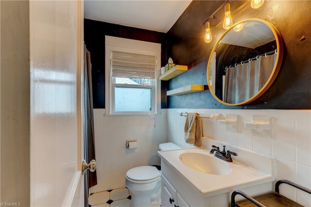 bathroom with wainscoting, toilet, tile walls, and vanity