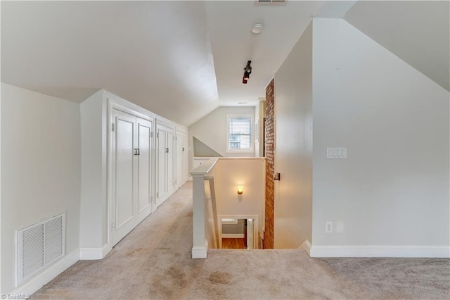 hall with visible vents, an upstairs landing, lofted ceiling, and light carpet