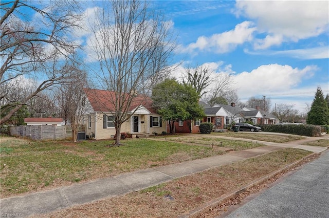 view of front of house with cooling unit, a front lawn, and fence