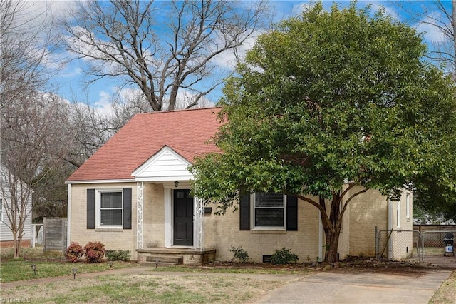 view of front of house with a gate, fence, brick siding, and a shingled roof