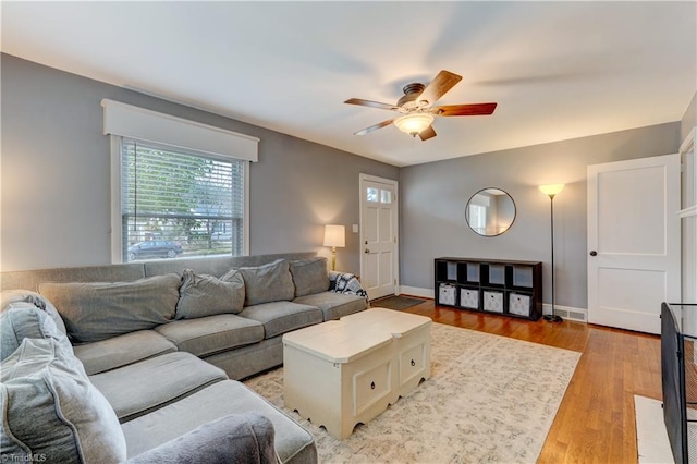 living area with a ceiling fan, light wood-type flooring, and baseboards