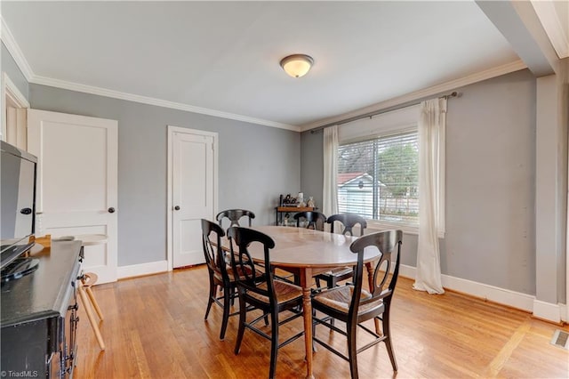 dining room with visible vents, baseboards, light wood-style floors, and ornamental molding