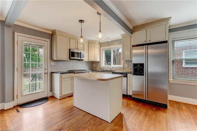 kitchen featuring stainless steel appliances, cream cabinetry, ornamental molding, and light wood-style flooring