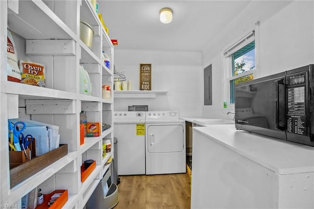 laundry area with electric panel, sink, independent washer and dryer, and light hardwood / wood-style floors