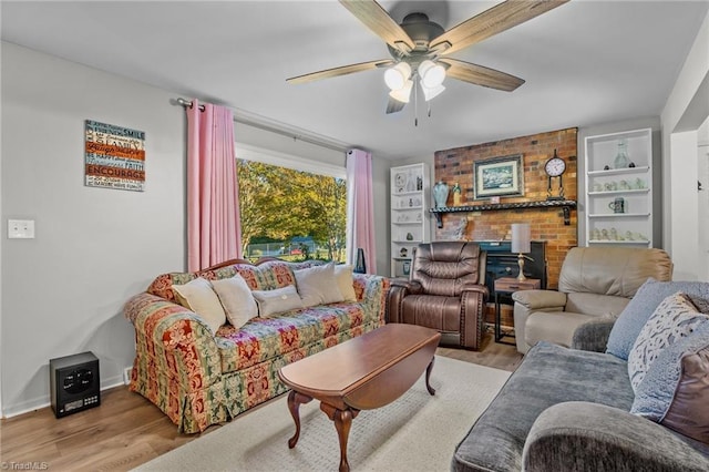 living room with ceiling fan, a brick fireplace, and light wood-type flooring