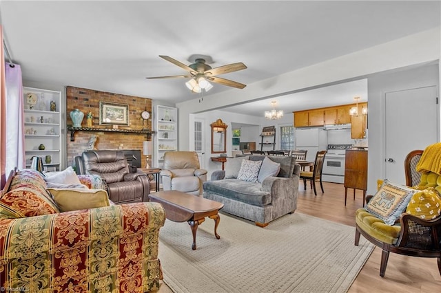 living room featuring light hardwood / wood-style flooring, a fireplace, and ceiling fan with notable chandelier