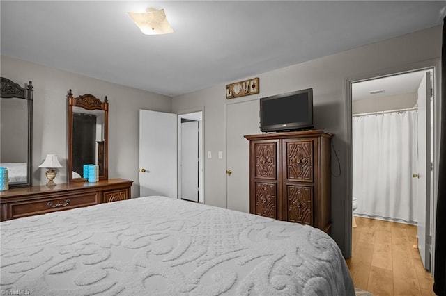 bedroom with ensuite bathroom and light wood-type flooring