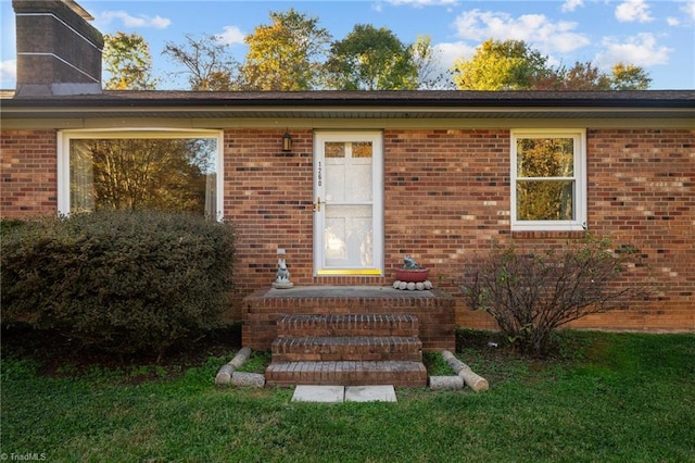 view of exterior entry with a lawn