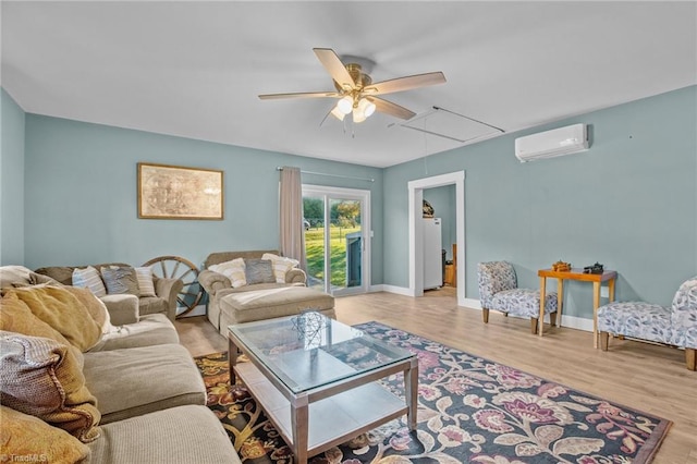 living room with light hardwood / wood-style floors, a wall unit AC, and ceiling fan