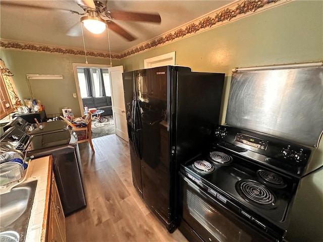 kitchen with sink, light hardwood / wood-style flooring, ceiling fan, and black appliances