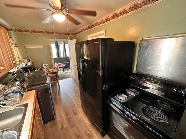 kitchen featuring ceiling fan, crown molding, black appliances, and light hardwood / wood-style floors