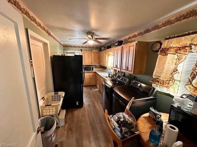 kitchen featuring washing machine and clothes dryer, ceiling fan, black refrigerator, and hardwood / wood-style floors