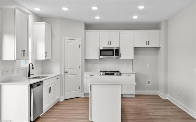 kitchen featuring a center island, white cabinets, sink, light wood-type flooring, and stainless steel appliances