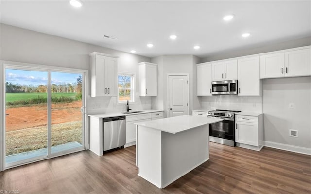 kitchen with a center island, backsplash, white cabinets, sink, and appliances with stainless steel finishes