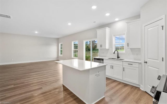 kitchen with light hardwood / wood-style flooring, white cabinetry, a kitchen island, and sink