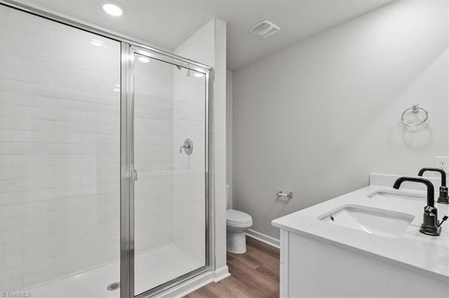 bathroom with hardwood / wood-style flooring, vanity, toilet, and walk in shower